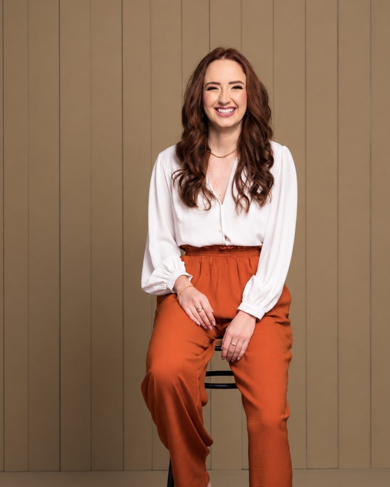 Dra. Juliana Pullig, médica em Goiânia, sorrindo, sentada em um banco